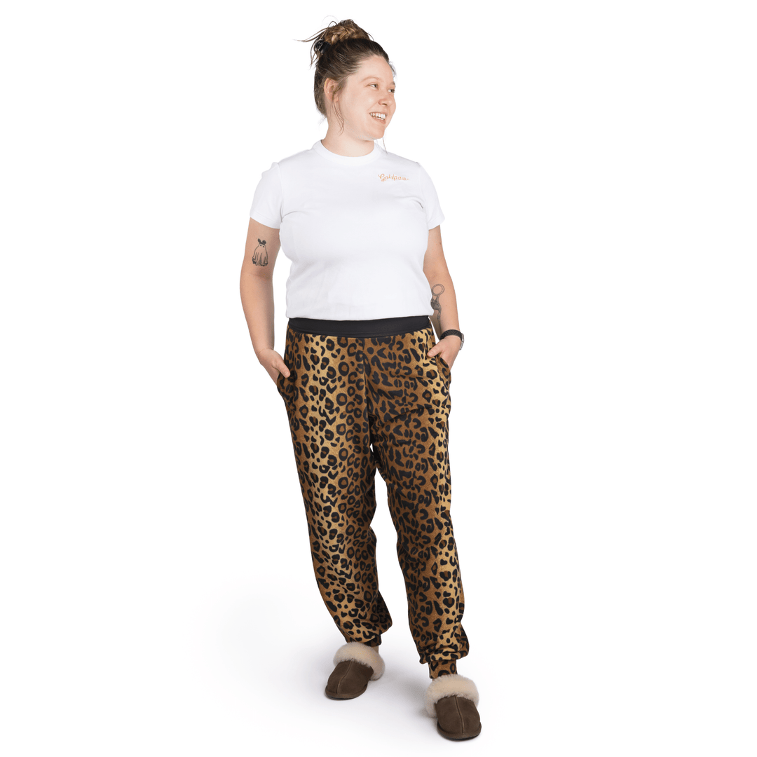 A woman stands wearing a white t shirt and leopard fleece joggers in front of a white background