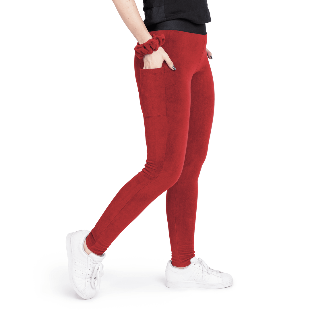 A woman wears red leggings in front of a white background