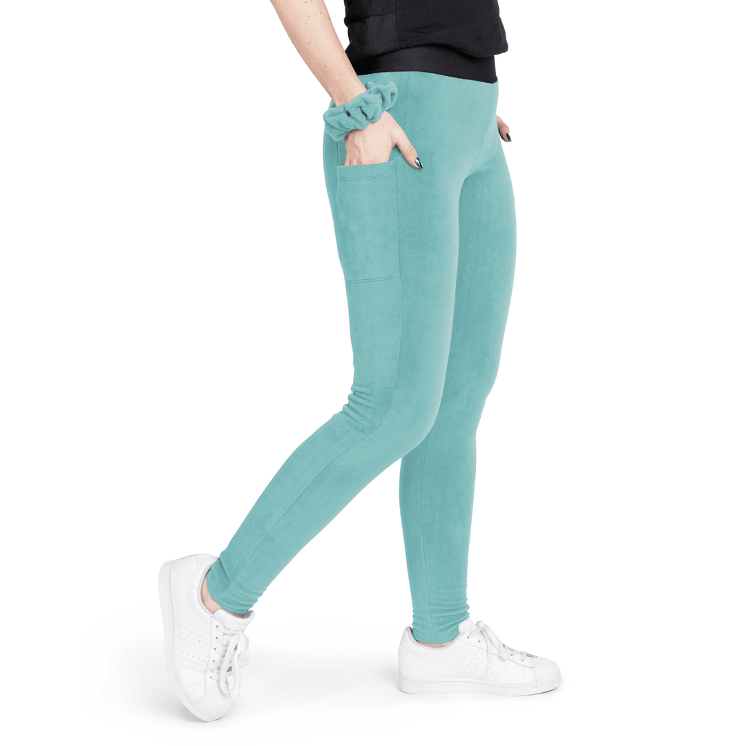 A woman wears turquoise leggings in front of a white background