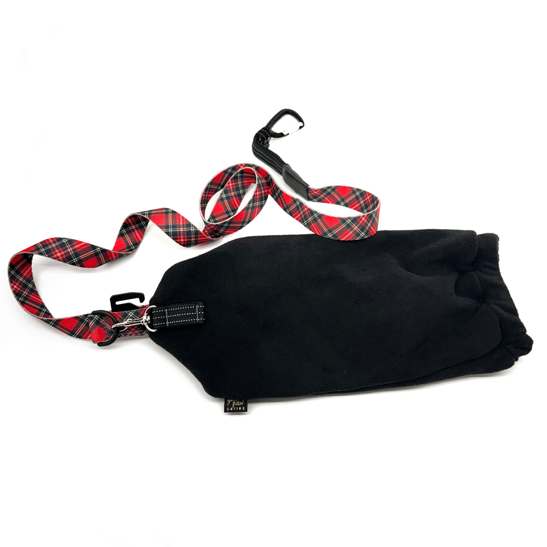 A black leash mitten with a red plaid dog leash attached to it in front of a white background