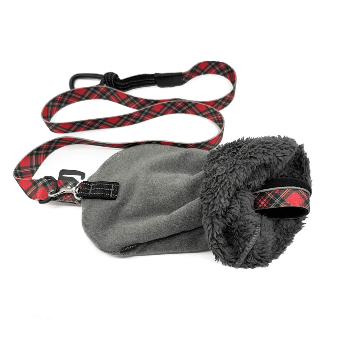 A charcoal leash mitten with a red plaid dog leash attached to it in front of a white background