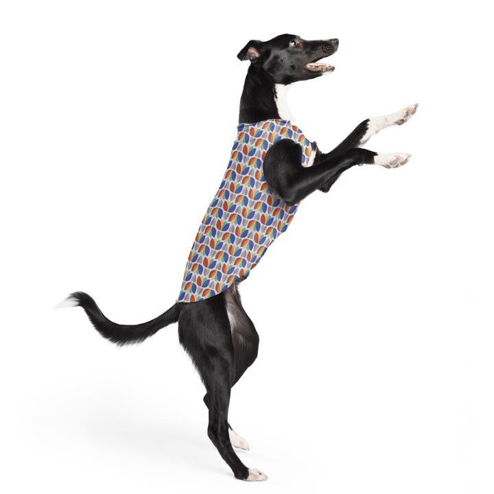 A dog jumps wearing a multicolored tulip pattern Sun Tee in front of a white background